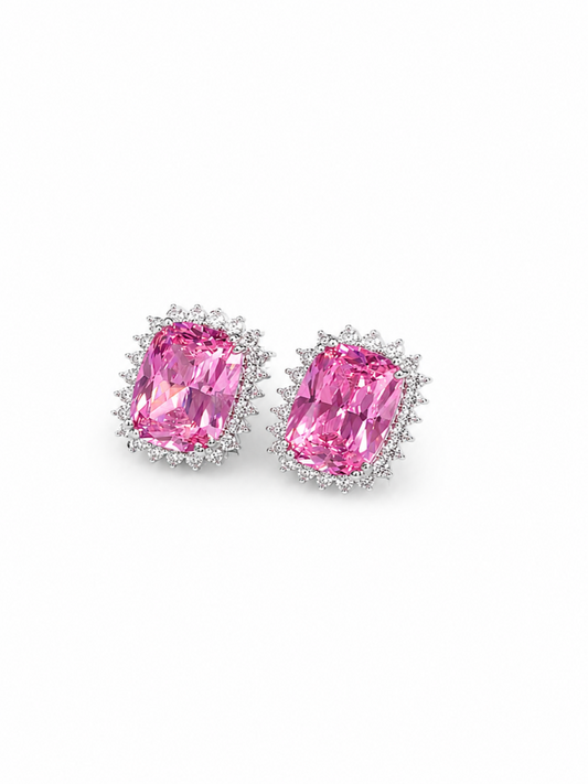 A pair of stud earrings featuring large emerald-cut pink gemstones in silver-toned settings with small clear accent stones, shown on a plain white background.