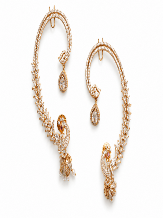 A pair of ornate gold-toned hoop earrings decorated with pavé-set clear stones and featuring peacock motifs with teardrop dangling accents, shown on a plain white background.