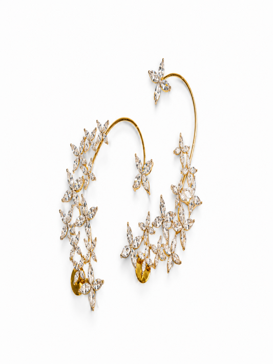 A pair of gold ear cuffs decorated with numerous clear marquise-cut gemstones arranged in starburst and floral clusters, set against a plain white background.