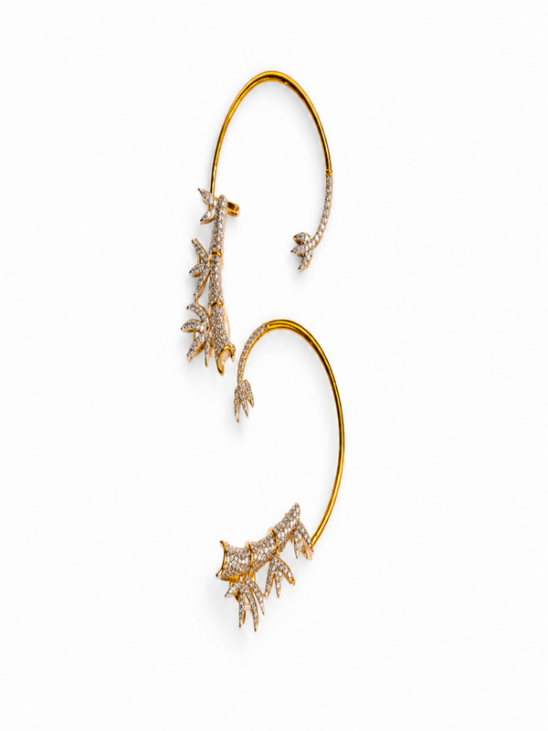 A pair of gold ear cuffs decorated with delicate coral-like clusters of clear pavé stones, displayed on a clean white background.