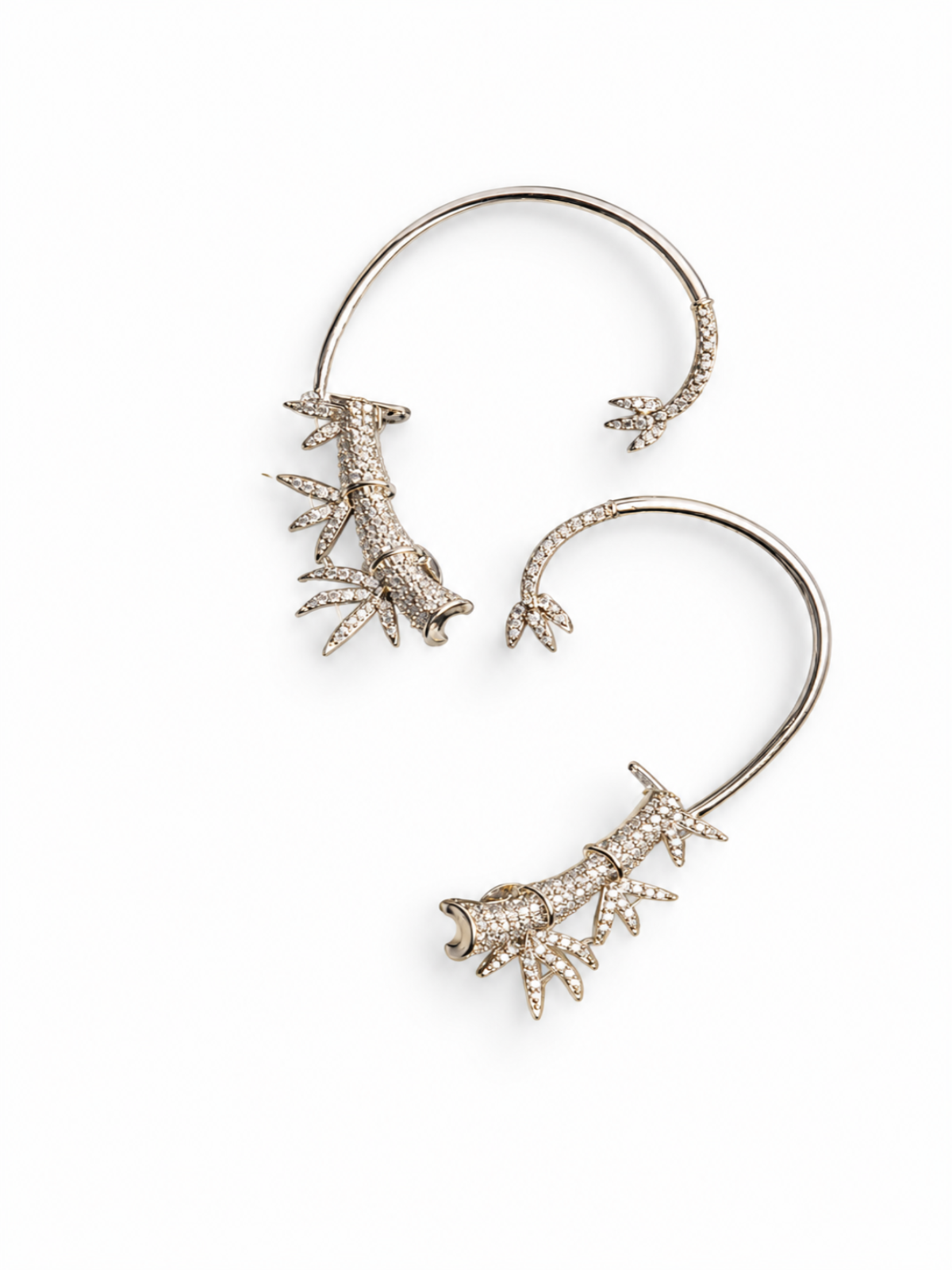 A pair of silver-toned ear cuffs decorated with detailed, textured coral-like motifs paved with small clear rhinestones, shown on a plain white background.
