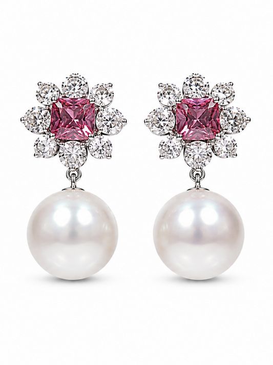 A pair of drop earrings featuring a central square pink gemstone surrounded by small clear stones, with a large white pearl hanging below, shown on a plain white background.