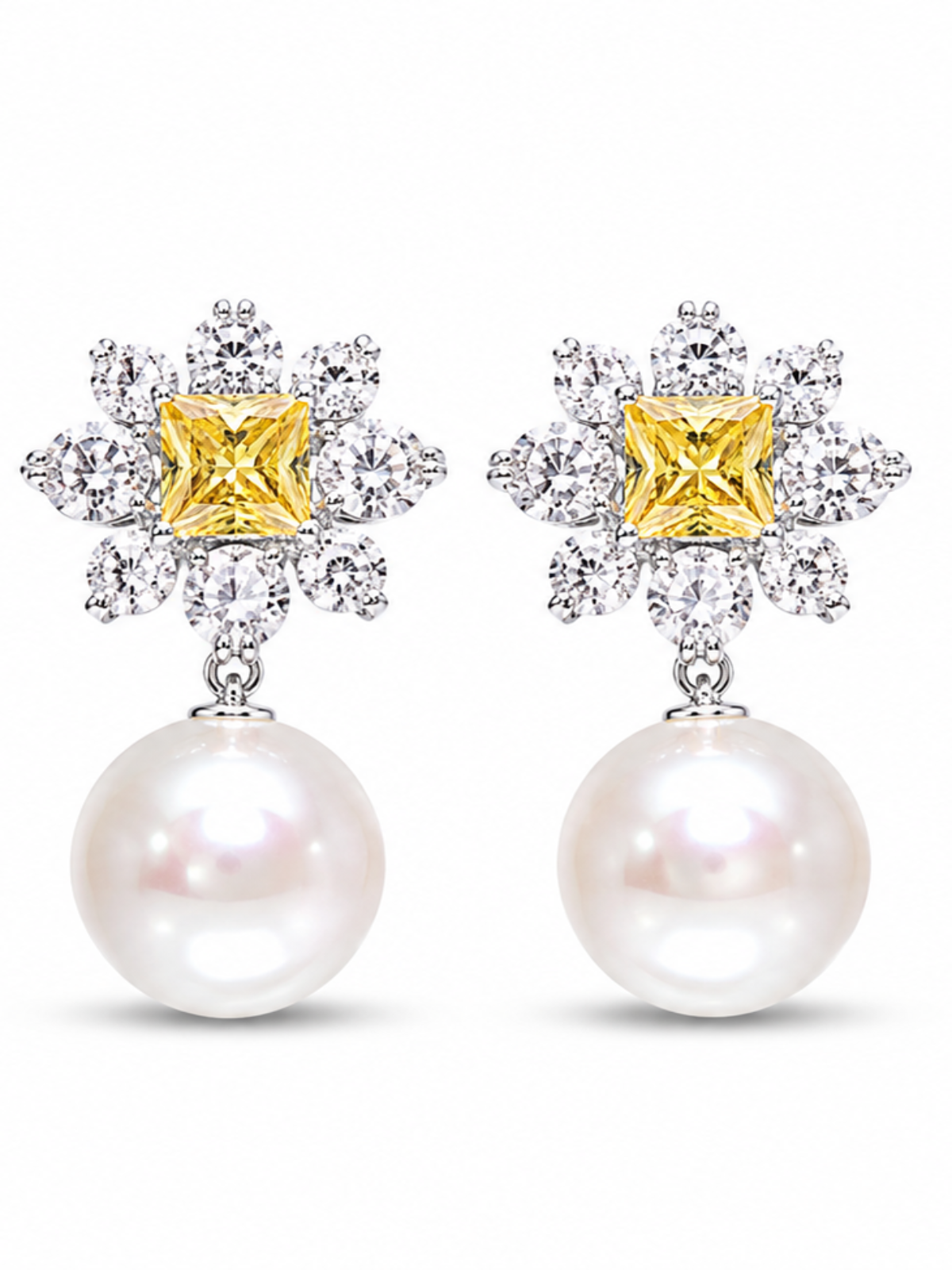 A pair of stud earrings featuring a yellow diamond-cut center stone surrounded by clear pavé-set stones, with a dangling white pearl below, shown on a plain white background.
