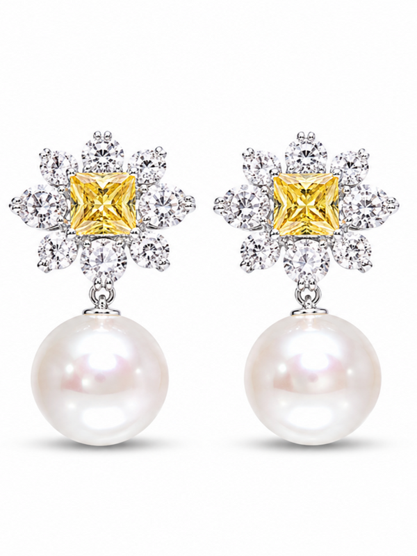 A pair of stud earrings featuring a yellow diamond-cut center stone surrounded by clear pavé-set stones, with a dangling white pearl below, shown on a plain white background.