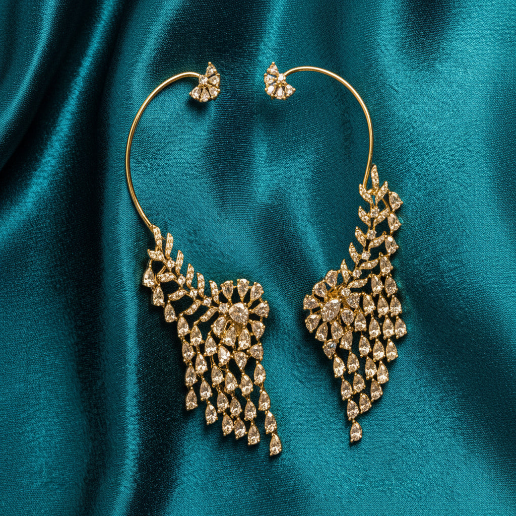 A pair of large hoop earrings with intricate diamond clusters in a silver-toned setting, displayed on a draped teal satin fabric background.